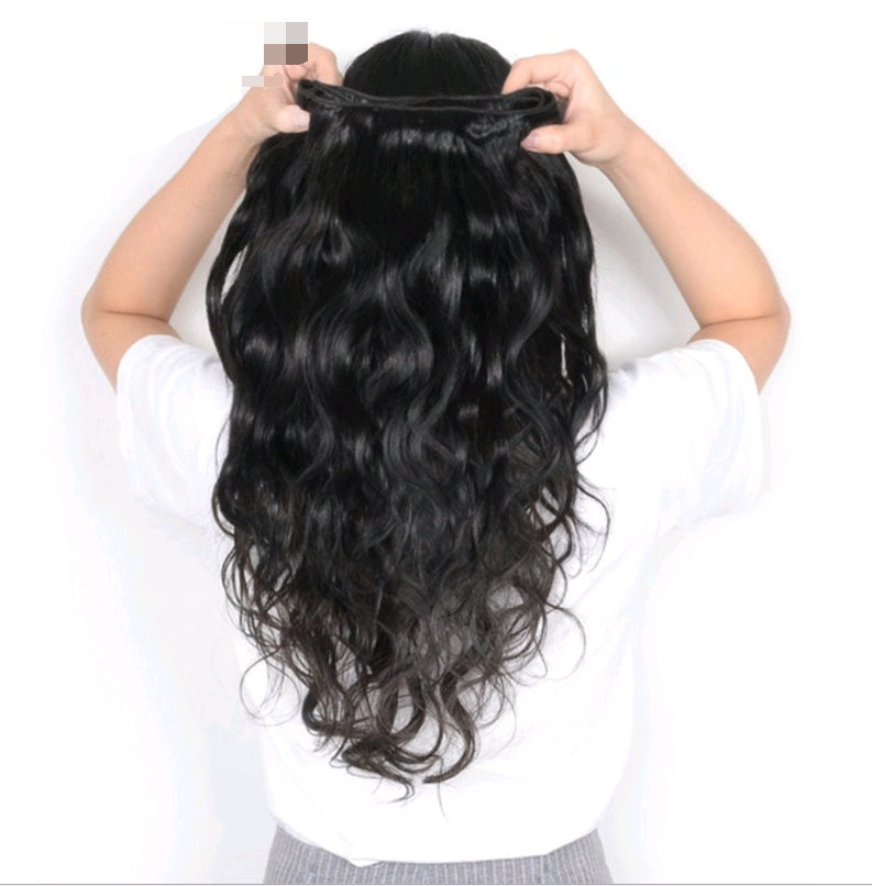 Person holding a black wavy hair extension against a white background